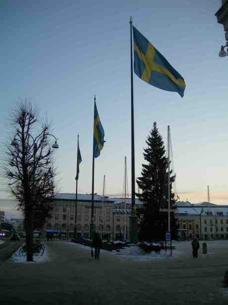 Gustaf Adolfs Torg flaggar på Nobeldagen medan Harry Persson spelar på Café Festival. Måndag 10 december 2012 kl 15.12.