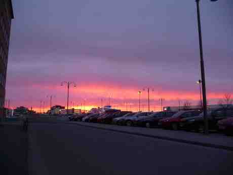 Solen går ner över Stenaterminalen vid Masthuggskajen. Men i rosenrött! Och sakta – borta 2020. Tisdag 25 mars 2014 kl 18:40.