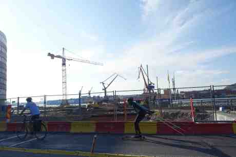 Götaverkens docka kvar, kan man se bortom pågående ombyggnaden av  Stenpiren och Skeppsbron. Rullskidåkare passerar på Stora badhusgatan ungefär där badhuset Rotundan låg. Onsdag 18 september 2014 kl 16:29.
